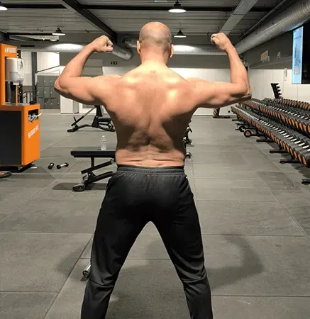 Ashish seen from behind with both arms raised, back muscles flexed