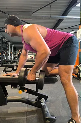 Ashish rowing a dumbbell with one knee and one hand on a bench