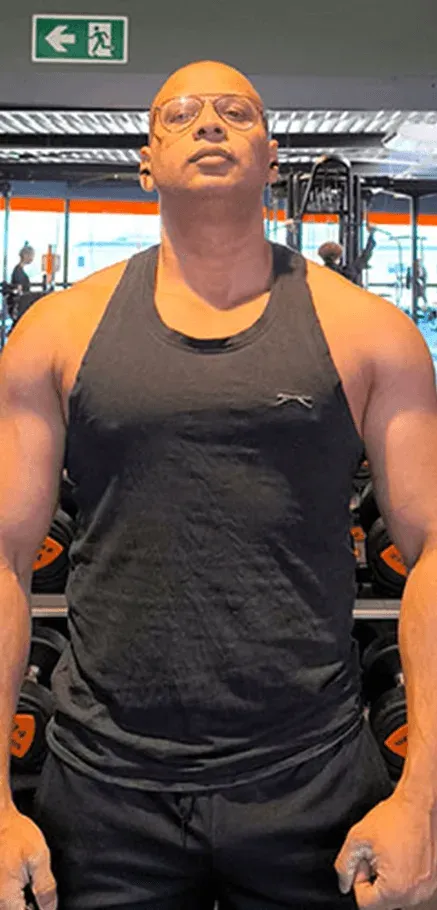 Ashish standing in front of a dumbbell rack, facing the camera