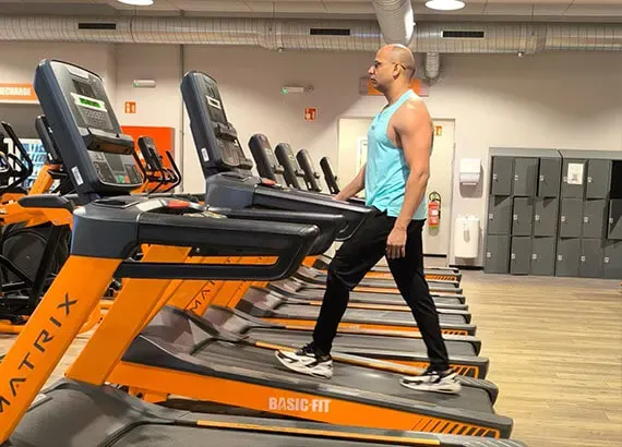 Ashish walking on a treadmill in a row of cardio machines