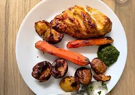 A plate of roast chicken with sweet potato, carrot and a green sauce